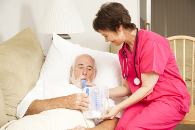 home health nurse helps a senior patient with his respiratory therapy